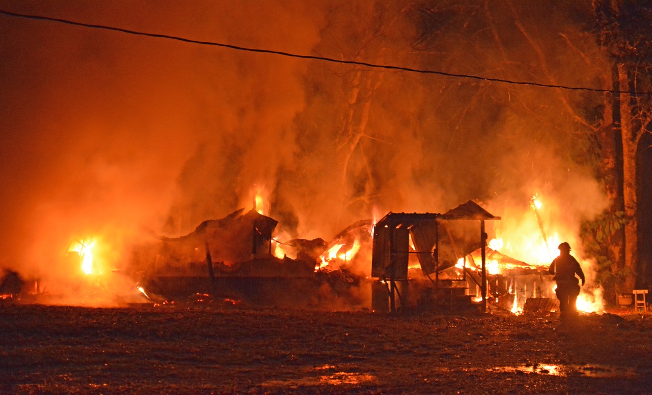 A lone firefighter evaluates the fire prior to implementing attack on a mobile home on Lake Aldwell Road that burned Thursday night. Jay Cline/Clallam County Fire District 2