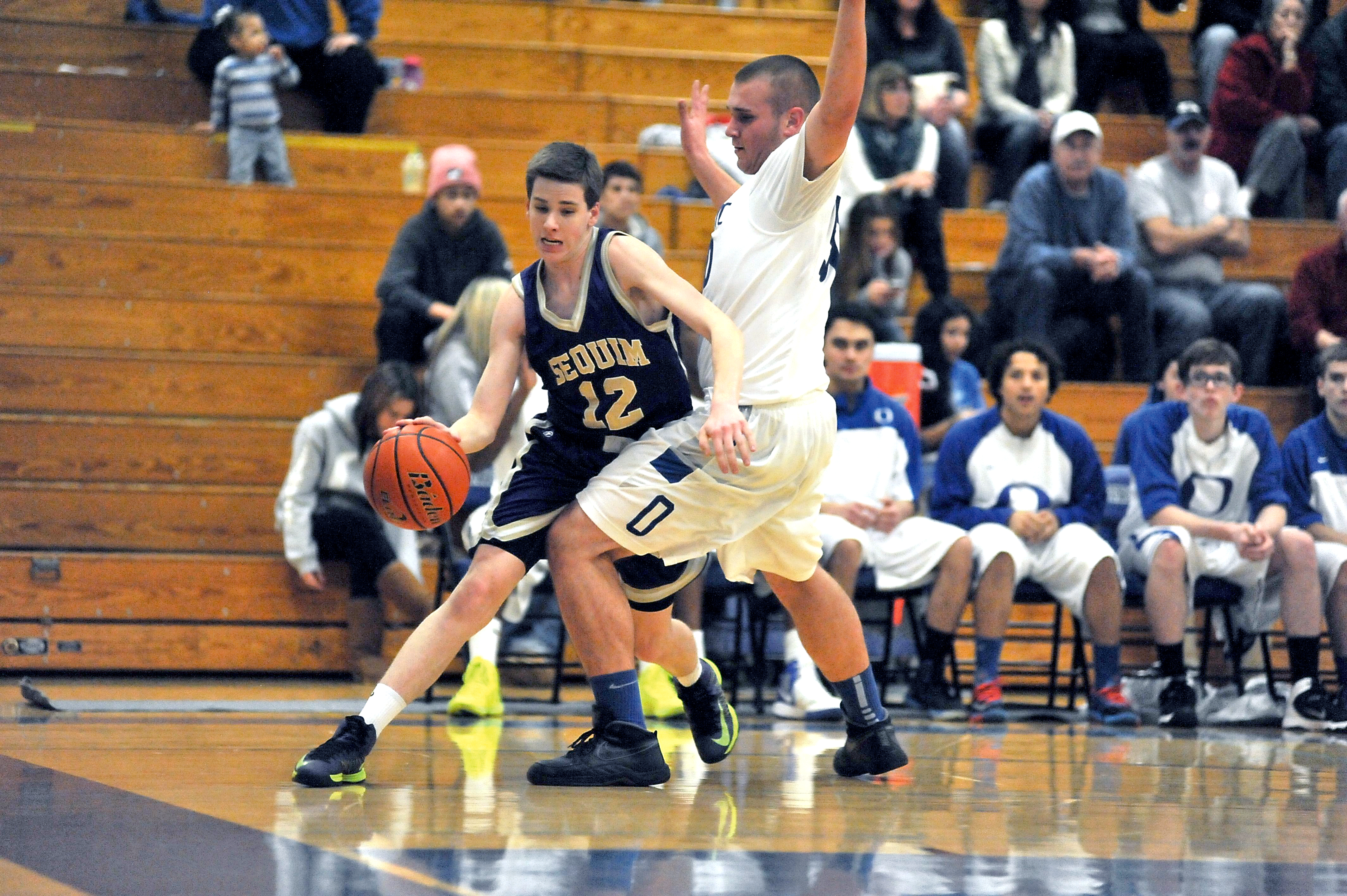 Sequim's Vance Willis (12) tries to get around Olympic's Darren Towne (50) during the Wolves' overtime win over the Trojans at Olympic High School. Jeff Halstead/for Peninsula Daily News