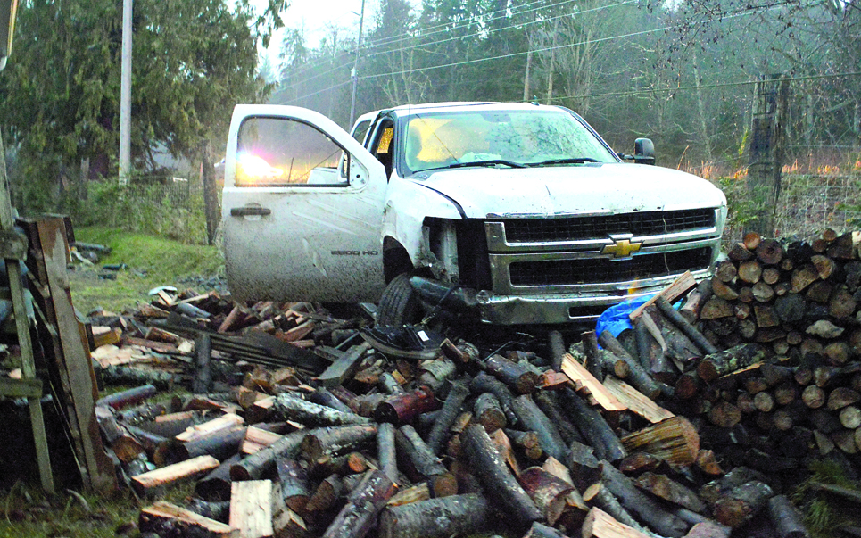 Clallam County PUD Commissioner Hugh Haffner's 2009 Chevrolet Silverado sits in the woodpile where it came to a halt after Haffner drove off U.S. Highway 101 earlier this week. Joe Smillie/Peninsula Daily News