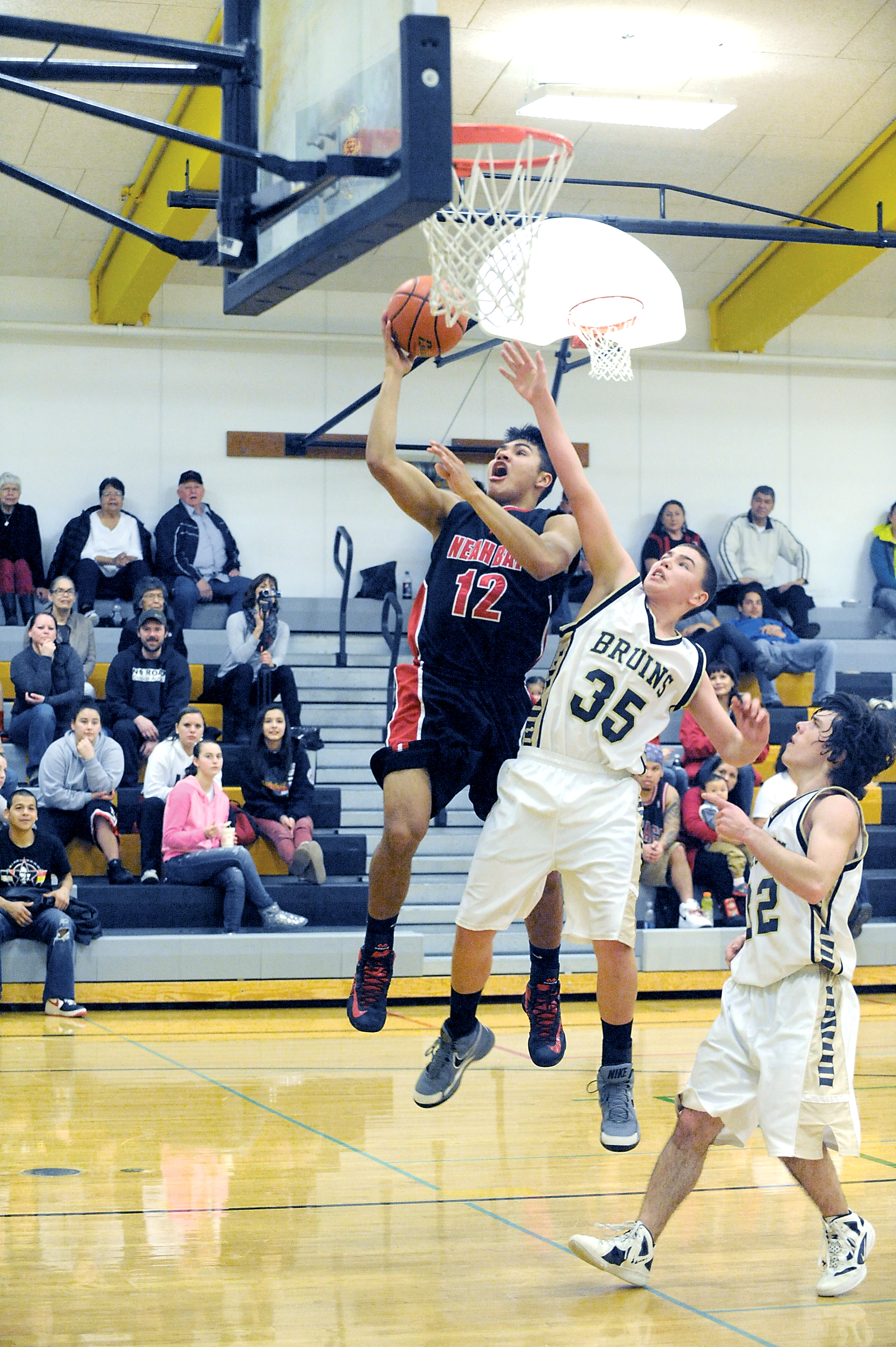 Neah Bay's Josiah Greene (12) puts up a shot over Clallam Bay's Dakotah Cowdrey (35) during the top-ranked Red Devils' league win over the Bruins. Lonnie Archibald/for Peninsula Daily News