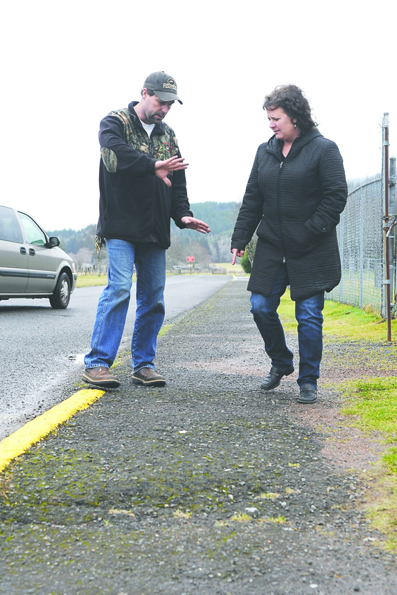 School maintenance supervisor Bill Henderson and School District Superintendant Diana Reaume talk of needed repairs on a sidewalk near the school football field.  It is heavily used by Forks Elementary School students as well as parents for various sports activities. Lonnie Archibald/for Peninsula Daily News