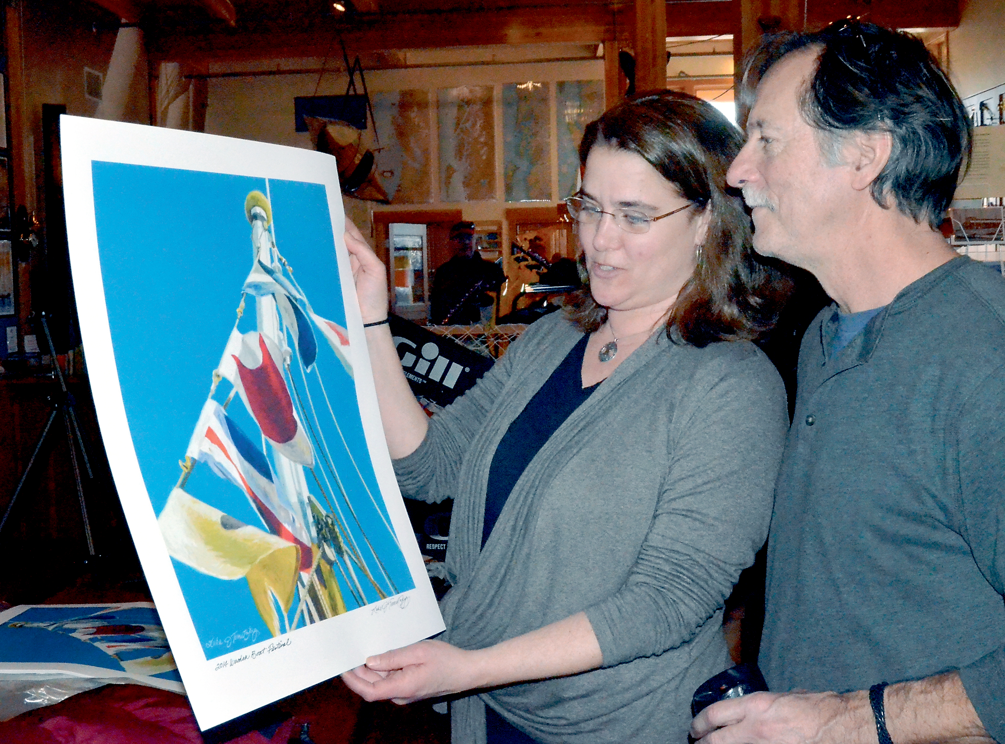 Wooden Boat Festival co-director Carrie Andrews inspects a print of this year's festival poster artwork with its artist