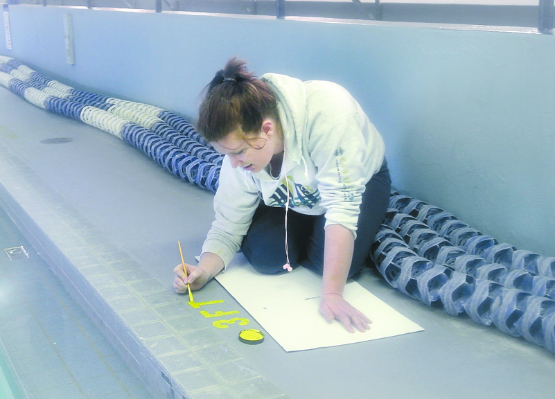 Mountain View pool manager Anji Scalf hand-paints depth markers at the pool