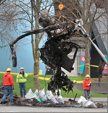 The twisted remnants of the KOMO news helicopter are removed from the crash site Tuesday. The Associated Press
