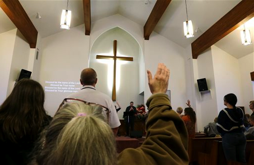 A member of the congregation at Glad Tidings Assembly of God church in Darrington raises her hand as she sings during Sunday morning church services. Much of the music and speaking was devoted to reaction to the deadly mudslide that hit the nearby community of Oso. The Associated Press