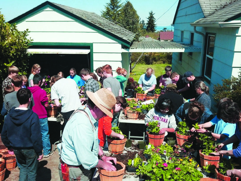 Members of the Northwinds Homeschool Band plant 400 hanging flowering baskets on April 22 in Port Angeles to raise funds for a 2014 performance tour through Southern California. The baskets are available for sale by calling 360-452-7189.