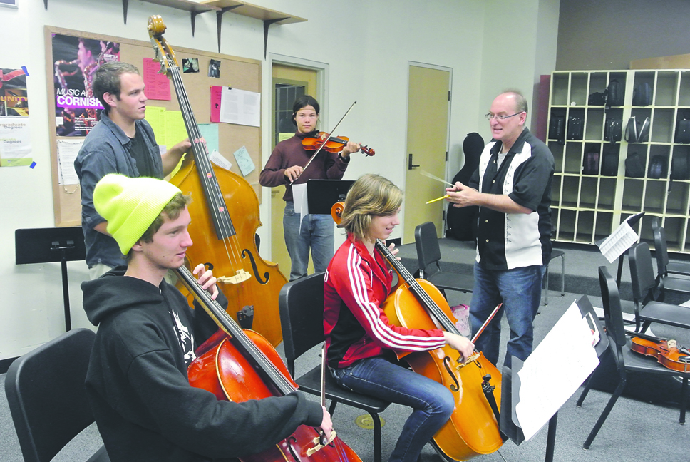 Port Townsend High School orchestra members (clockwise from lower left) Rory McDonald. Jake Van Vockli. Elijah Johnston and Alethea  Westlund get some last minute pointers from orchestra director Russell Clark in preparation for tonight's encore performance of "Sgt. Pepper's Lonely Hearts Club Band." Charlie Bermant/Peninsula Daily News