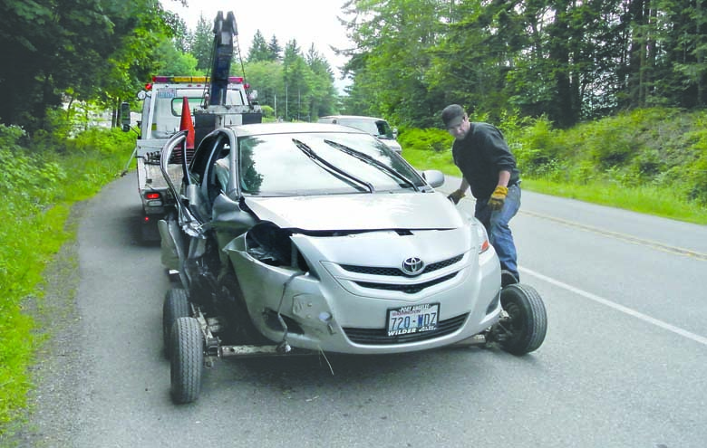 An unidentified tow truck driver prepares to haul a car that overturned on state Highway 20 on Friday. Charlie Bermant/Peninsula Daily News