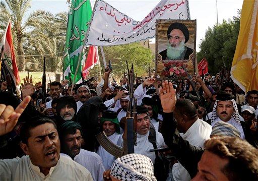 Shiite tribal fighters carry a poster of Shiite spiritual leader Grand Ayatollah Ali al-Sistani as they raise their weapons chanting against the al-Qaida-inspired Islamic State of Iraq and the Levant (ISIL) in Basra