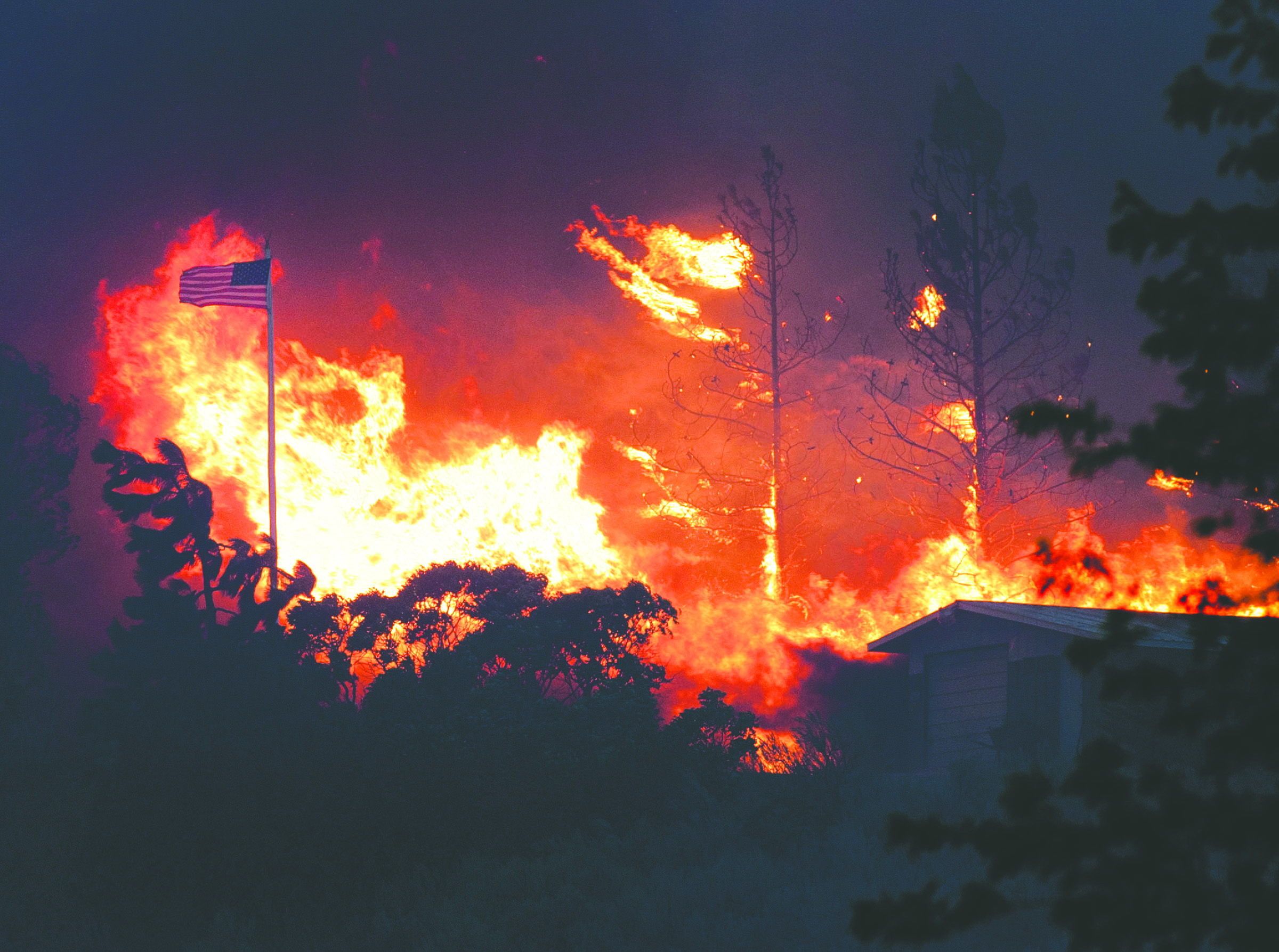 An American flag waves in the breeze as a wildfire approaches a home in Malott. The Associated Press