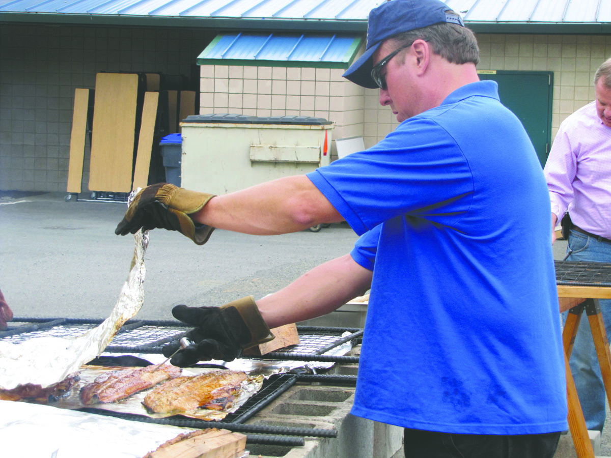 Rotarian Jay Patton checks the temperature on salmon baking on an outdoor grill at Sunday's Sequim Rotary salmon bake