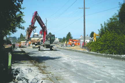 A work crew with Kent-based Scarsella Bros. Inc. works Tuesday to demolish the sidewalks on either side of the bridge that takes Lauridsen Boulevard over Peabody Creek. Jeremy Schwartz/Peninsula Daily News