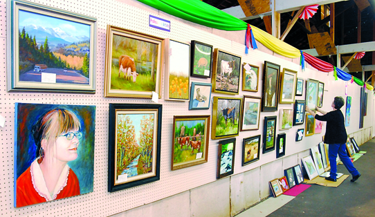 Volunteer Mary Marsh of Sequim arranges artworks in the Artists Building at the Clallam County Fairgrounds on Tuesday. The Clallam County Fair begins its four-day run starting on Thursday in Port Angeles. Keith Thorpe/Peninsula Daily News