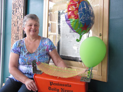 Third-generation Port Angeles resident Joan Morrish shows a retirement gift a fellow carrier gave her: A PDN delivery tube with a hammock made from string used to bundle newspapers. Arwyn Rice/Peninsula Daily News
