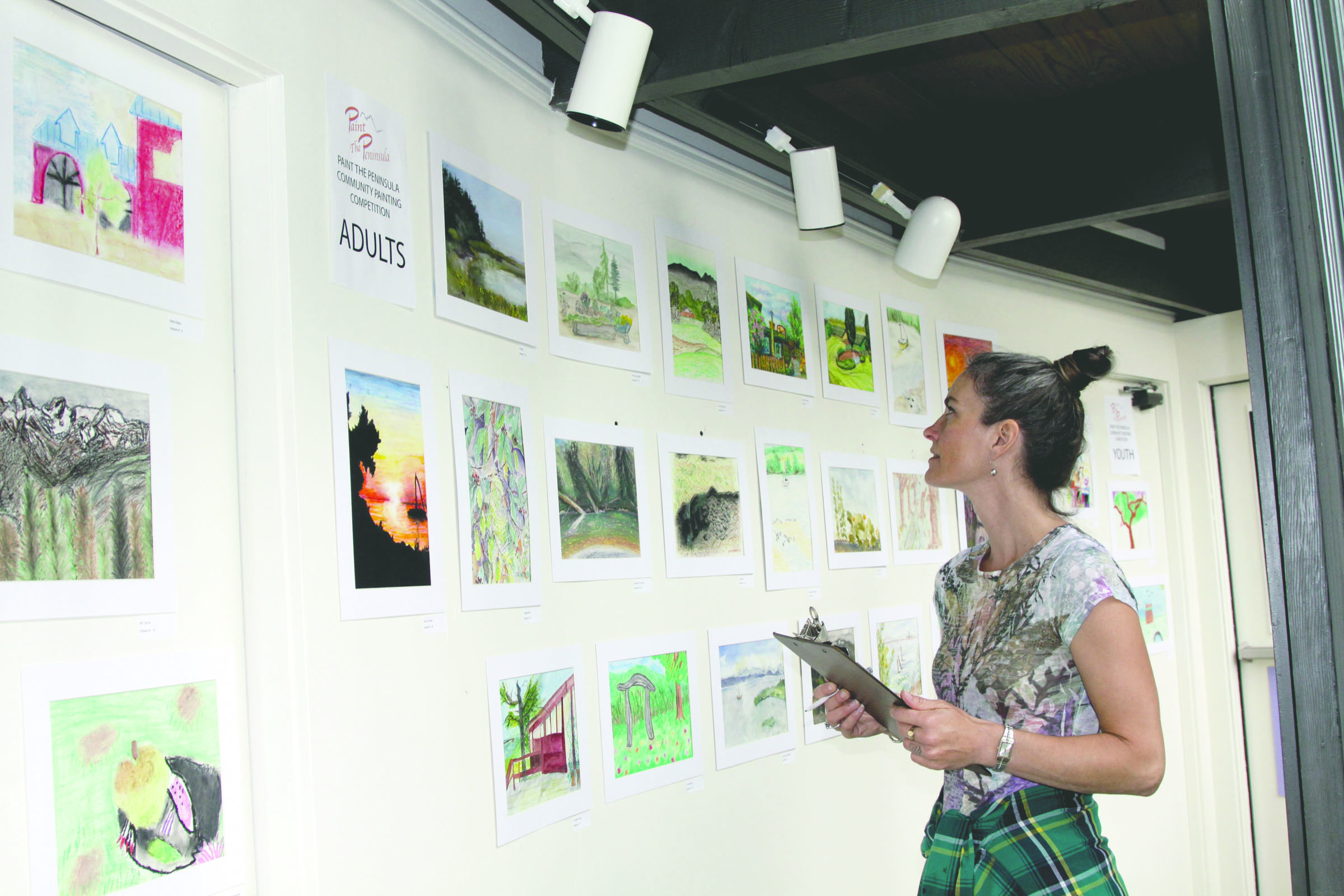 Cammie Watson of Victoria peruses the Community Plein Air Contest entries on display Friday at the Port Angeles Fine Arts Center. The contest is part of the Paint the Peninsula festival
