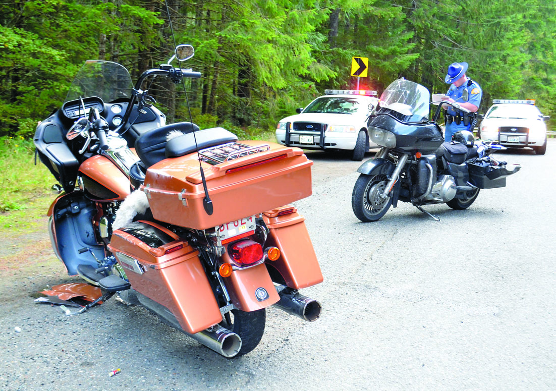 Trooper Matt Phillips investigates the motorcycle crash scene Monday on U.S. Highway 101. Charlie Bermant/Peninsula Daily News