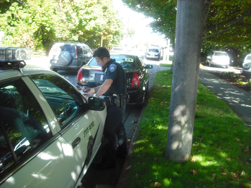 Port Angeles Deputy Police Chief Brian Smith fills out paperwork on the hood of a State Patrol car after hitting a Cadillac parked on Peabody Street with his squad car Monday. Margaret McKenzie/Peninsula Daily News