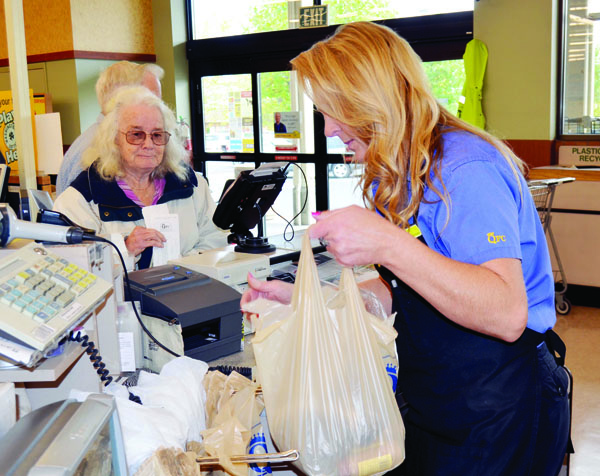 QFC checker Deb Boone loads Merna Hawks' groceries into plastic bags in Port Townsend on Wednesday. Charlie Bermant/Peninsula Daily News