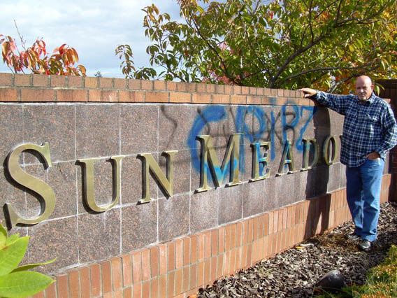 Sun Meadows Home Owners Association Vice President John Wilson stands near the tagged sign at the community's main entrance at West Sequim Bay Road and Independence Drive. Rob Ollikainen/Peninsula Daily News