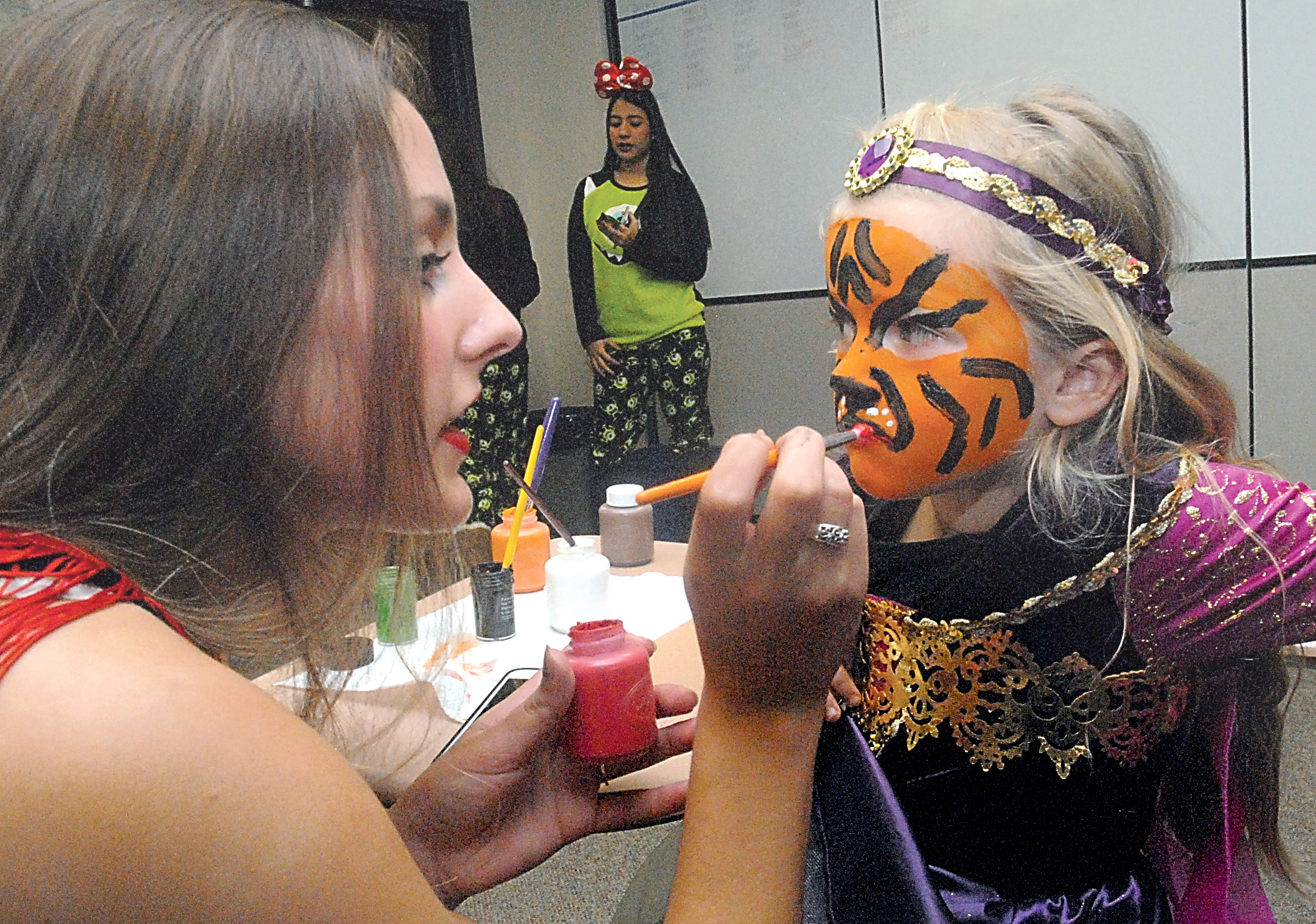 Five-year-old Emma Hughes of Port Angeles receives a tiger design on her face from Amanda Sanders