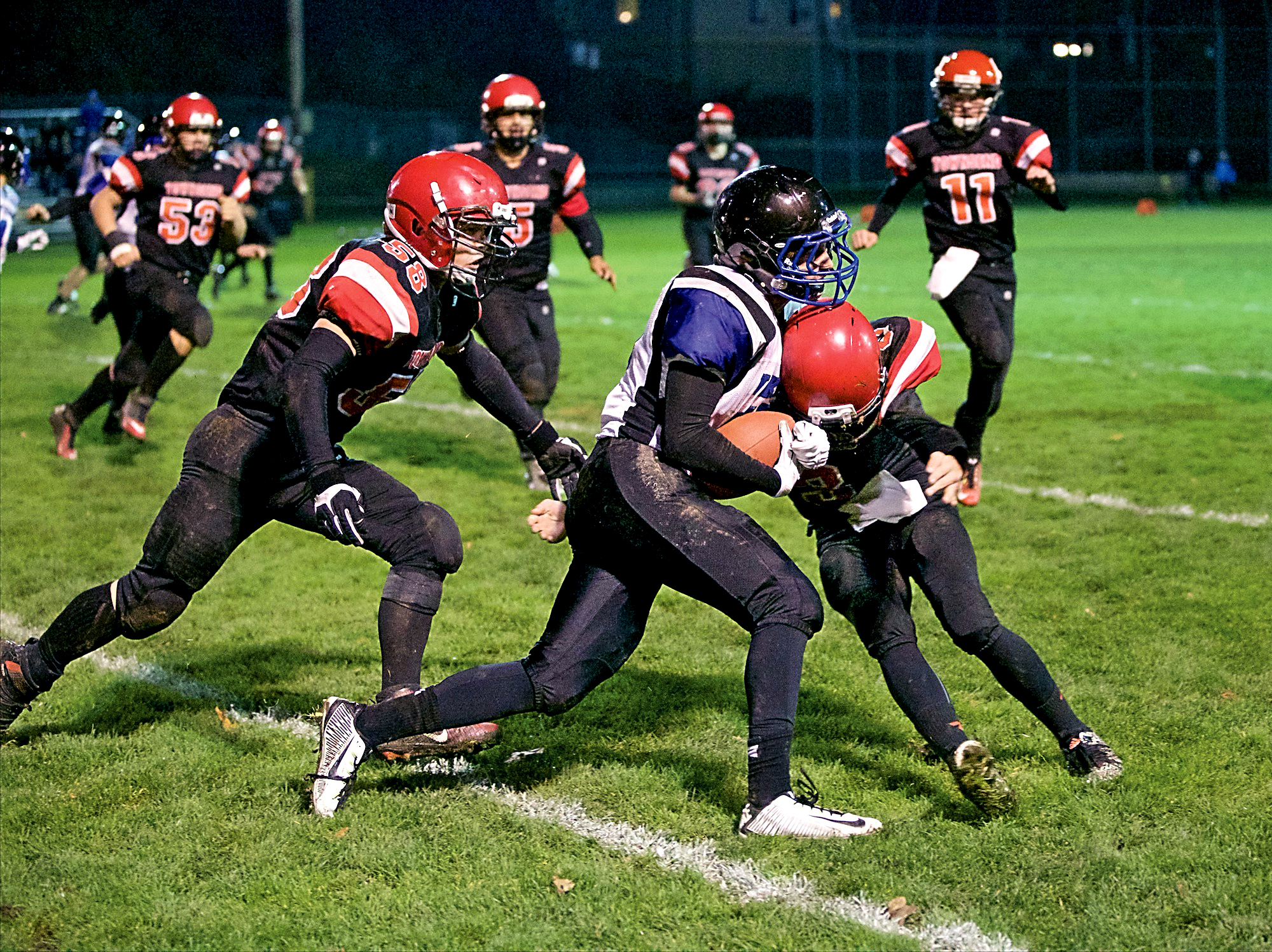 Port Townsend's Keegan Khile (58) and Jacob Ralls (3) stop the progress of Bellevue Christian's Dylan Parsons during the Redhawks' play-in game victory at Memorial Field in Port Townsend. Steve Mullensky/for Peninsula Daily News
