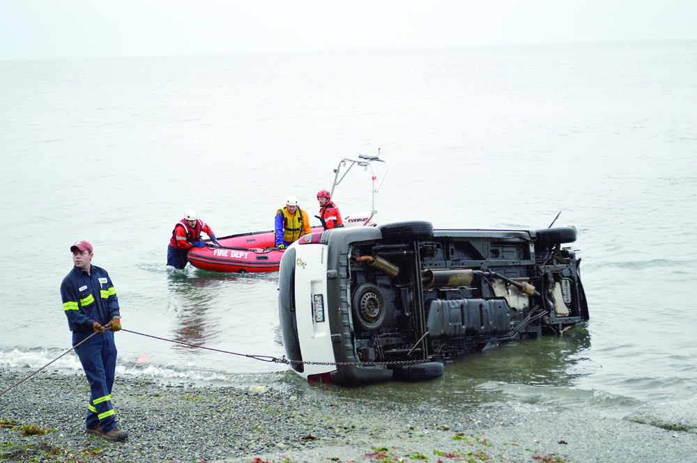 Evergreen Collision workers and crews from Clallam County Fire District No. 3 pull a minivan out of the Strait of Juan de Fuca at the Port Williams boat launch Saturday morning. Joe Smillie/Peninsula Daily News