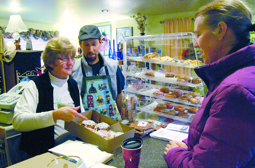 Debi and Courtland Gpetz serve fresh doughnuts to customer Wenkie Schultz at their shop