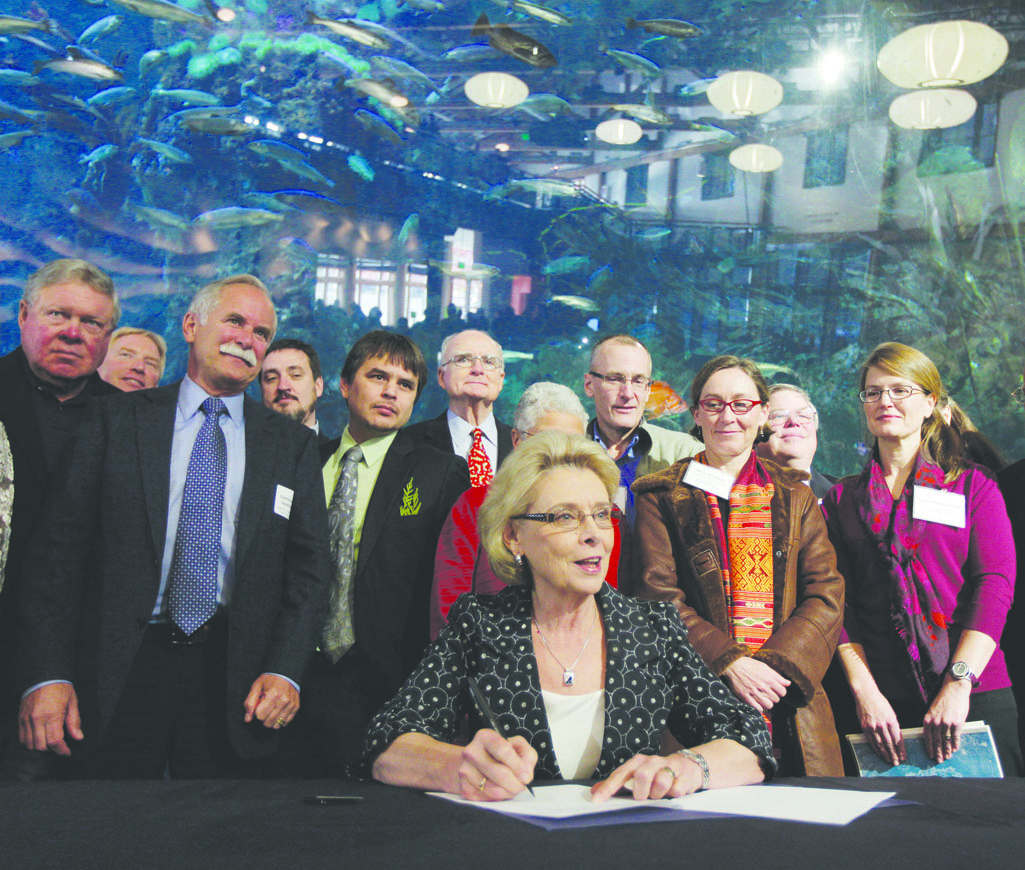 Gov. Chris Gregoire signs an order addressing ocean acidication on Nov. 27 at the Seattle Aquarium. At left is Rep. Norm Dicks