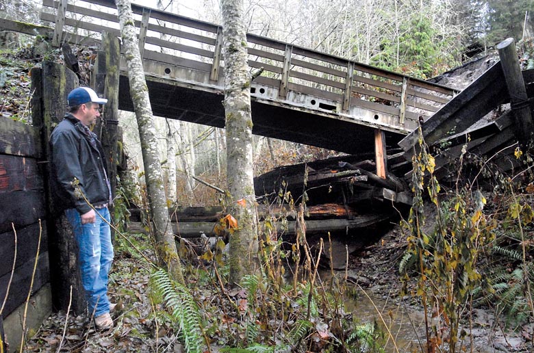 Shawn Gallacci looks at the shattered remains of the private bridge on Garling Road leading into his neighborhood east of Port Angeles on Saturday. Keith Thorpe/Peninsula Daily News