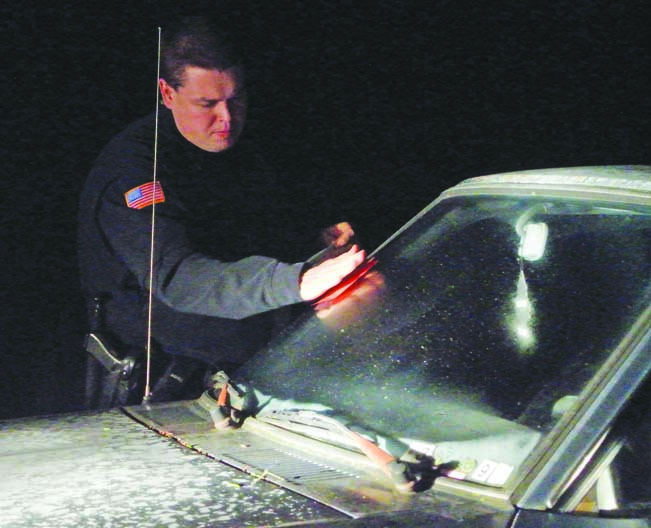 Port Townsend Officer Luke Bogues slaps an impound notice on an abandoned vehicle during his Saturday night shift