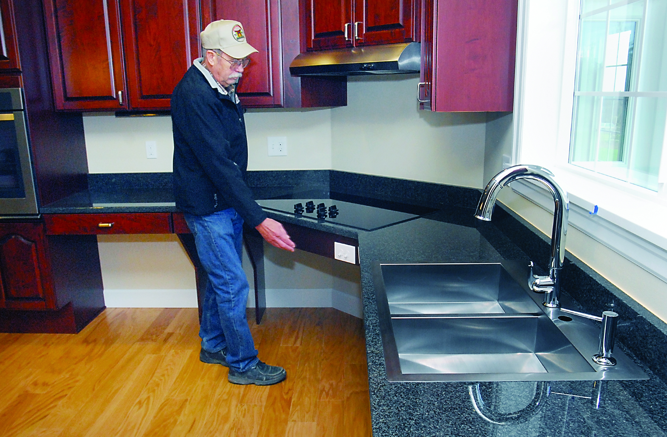 Jerry Hines of Hines Construction explains the workings of a custom kitchen designed to be wheelchair-friendly in a house built for Marine Cpl. Ammon Lang off O'Brien Road east of Port Angeles through the Homes for Our Troops program. Keith Thorpe/Peninsula Daily News