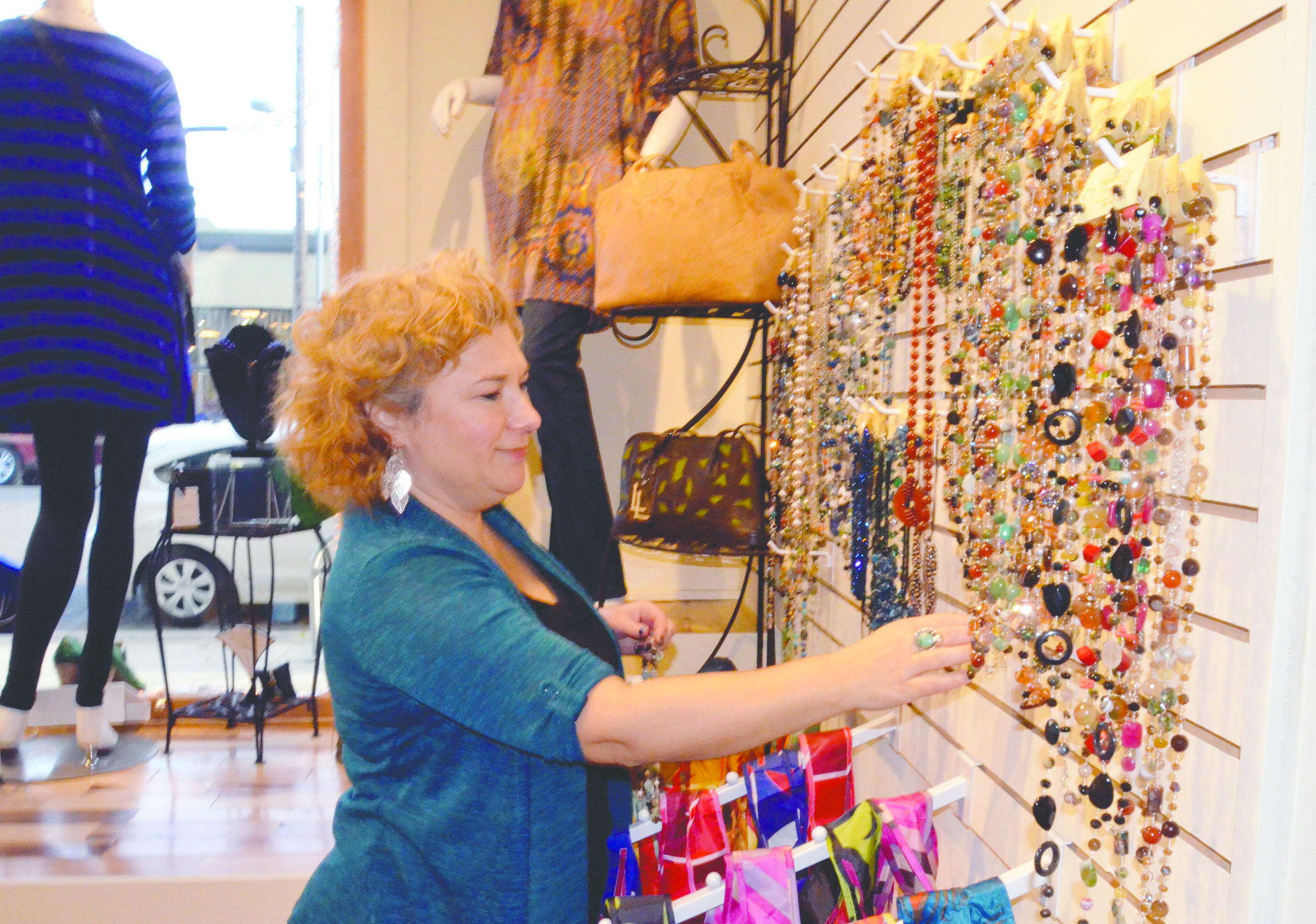 About Time owner Jeannine Kempees arranges the jewelry wall while preparing for reopening the store in its new location