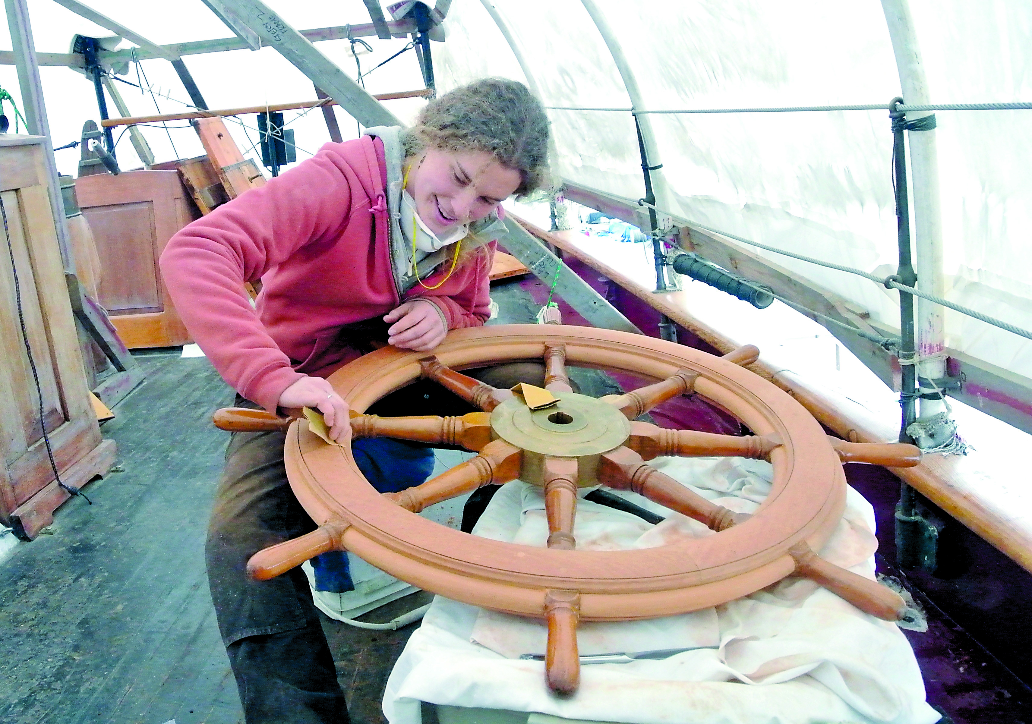 Alea Robertson polishes the newly acquired wheel for the schooner Adventuress in preparation for several coats of varnish. The wheel replaces one that was stolen in Olympia last summer.  -- Photo by Charlie Bermant/Peninsula Daily News