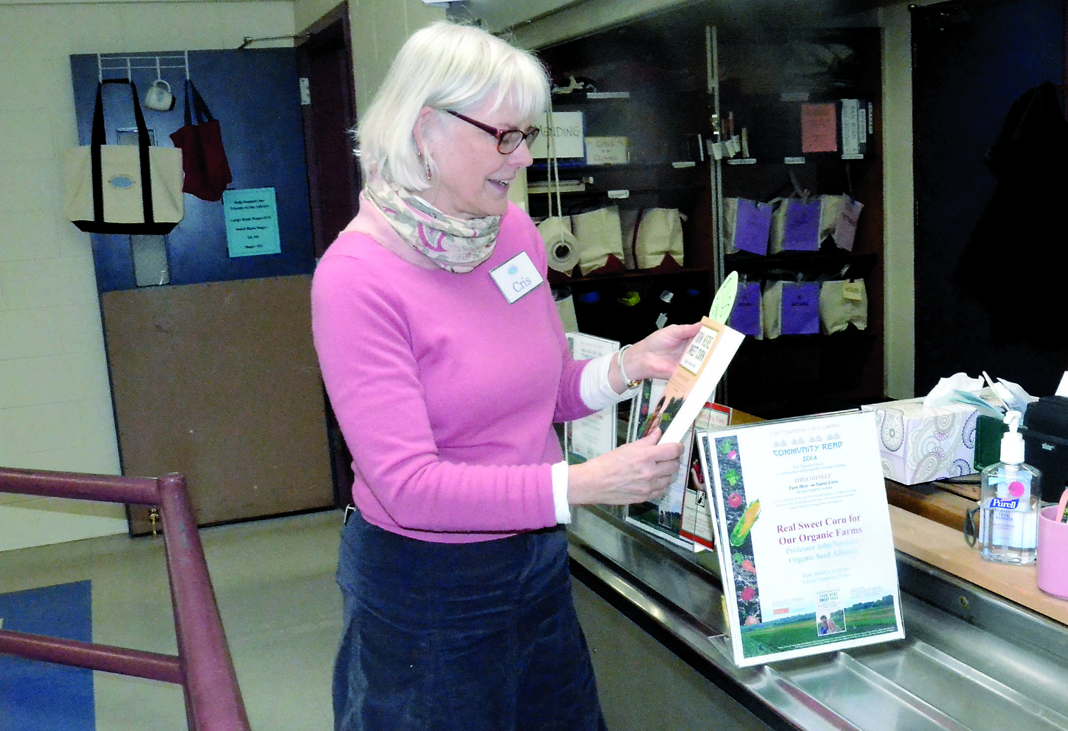 Port Townsend Librarian Cris Wilson adjusts the display promoting this year’s Community Read with Atina Diffley’s Turn Here Sweet Corn. — Charlie Bermant/Peninsula Daily News