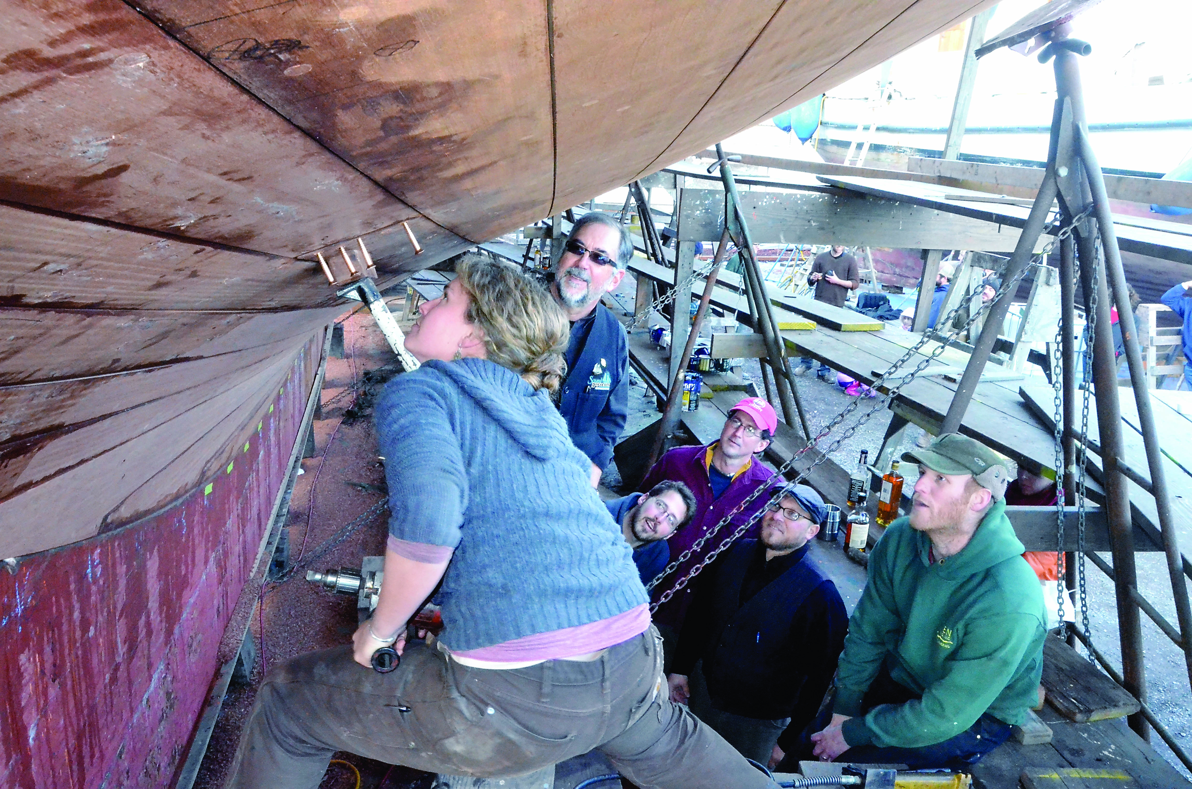 Alea Robertson screws in the last plank for the schooner Adventuress’ five year renovation under the watchful eyes of (from left) Sound Experience board chair Kenneth Greff