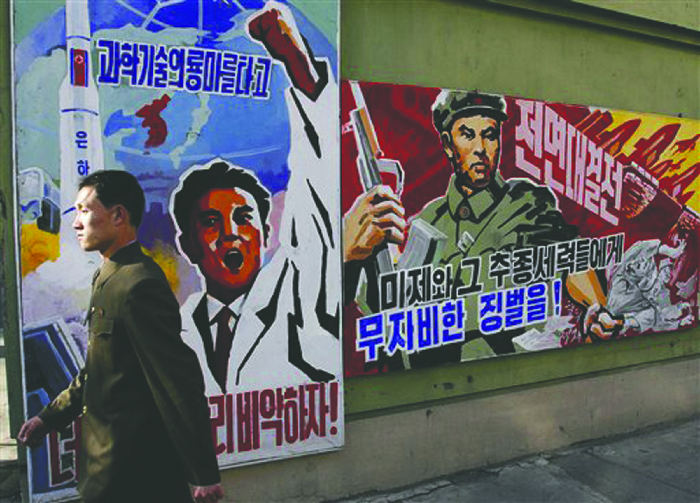 A North Korean man walks past propaganda posters in Pyongyang