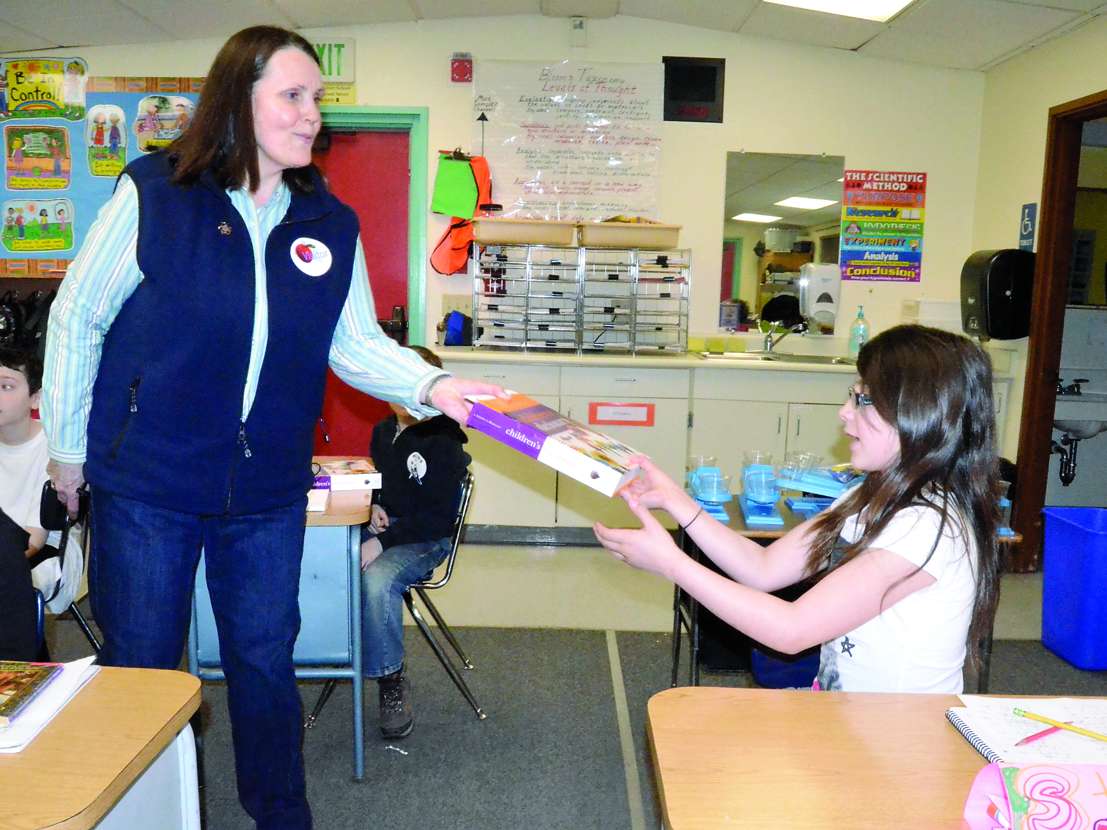 Sunrise Rotary member Rita Hubbard hands a dictionary to Stephanie Sanchez