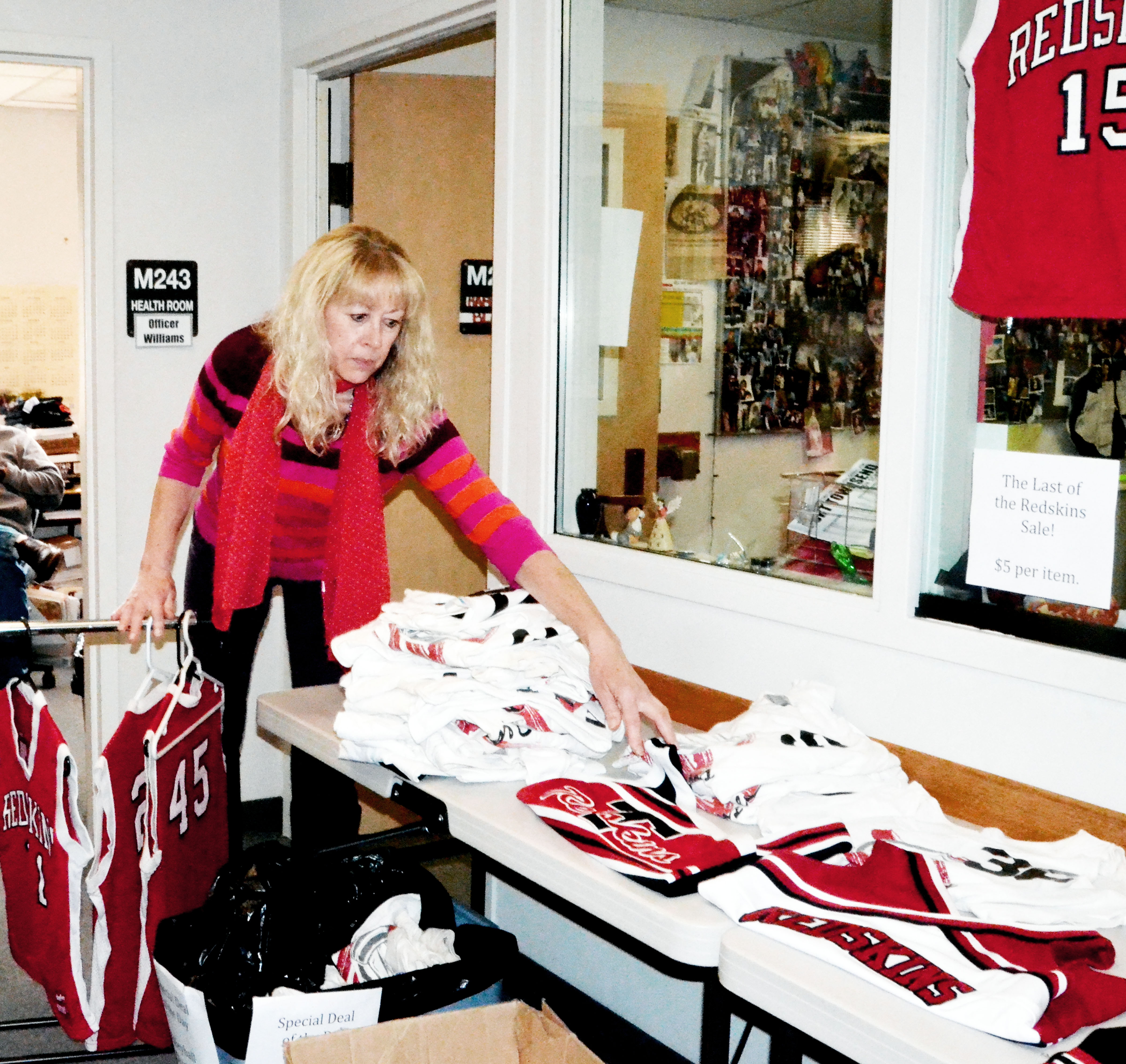 Port Townsend High School secretary Jan Boutilier arranges Redskins gear for sale Monday in preparation for the school's mascot change to Redhawks.  —Photo by Charlie Bermant/Peninsula Daily News
