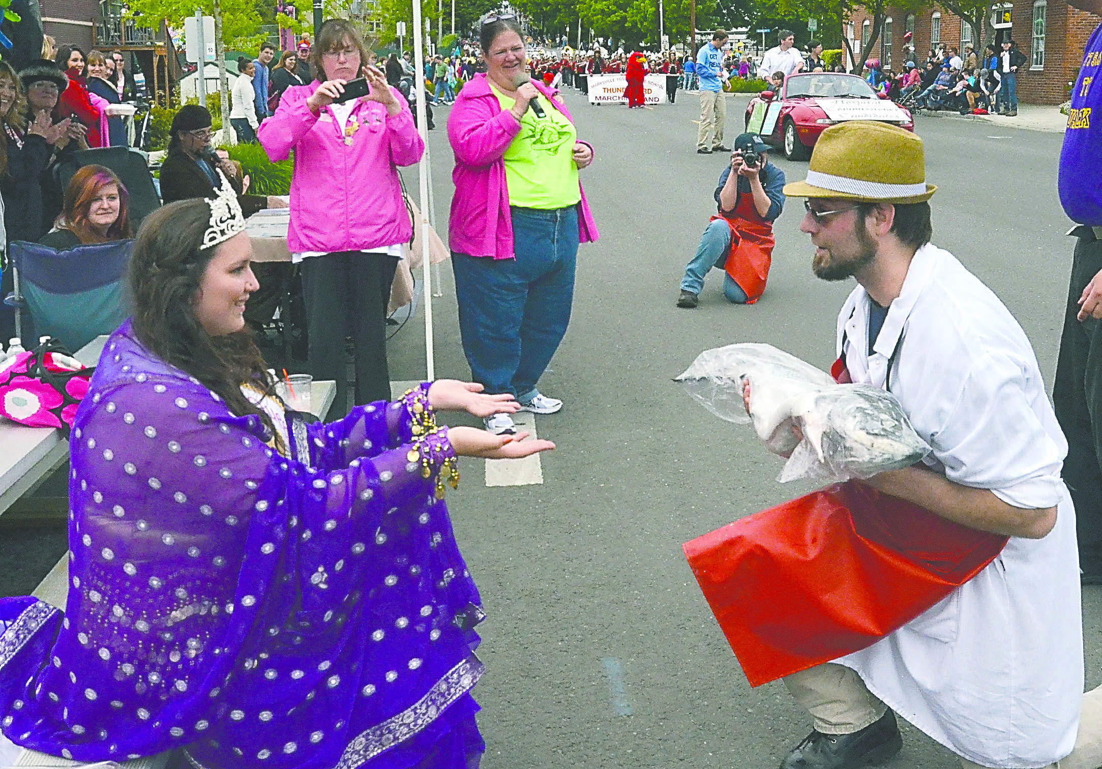 Rhody Festival Queen Emma White Thunder is presented with a whole salmon from Jacob Genaw of Key City Foods during the Grand Parade in Port Townsend on Saturday. -- Photo by Charlie Bermant/Peninsula Daily News