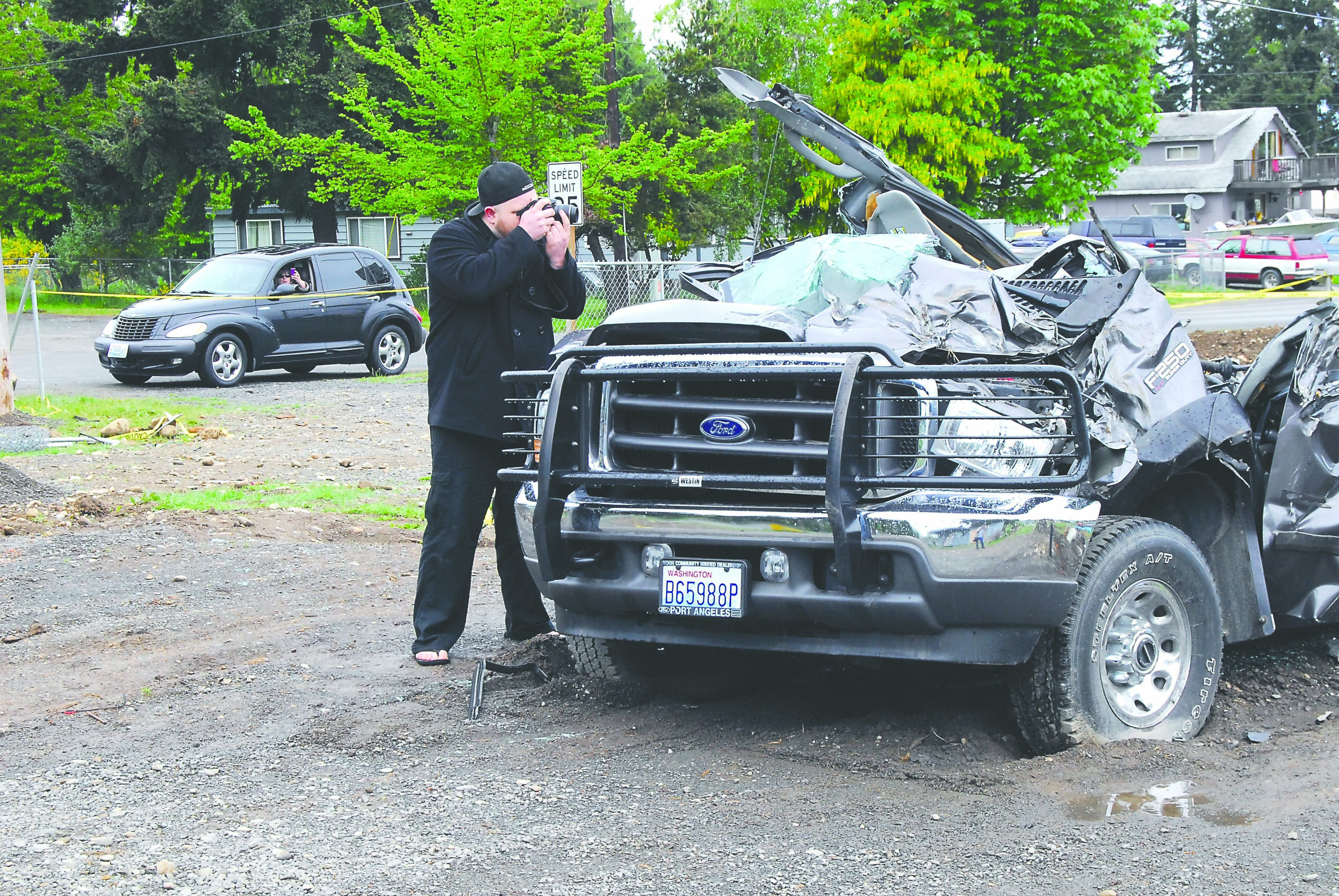Photography student Cody Kreider of Port Angeles takes photos of bulldozer-inflicted destruction on Baker Street in the Gales Addition east of Port Angeles on Friday as a motorist takes photos from a nearby car.   -- Photo by Keith Thorpe/Peninsula Daily News