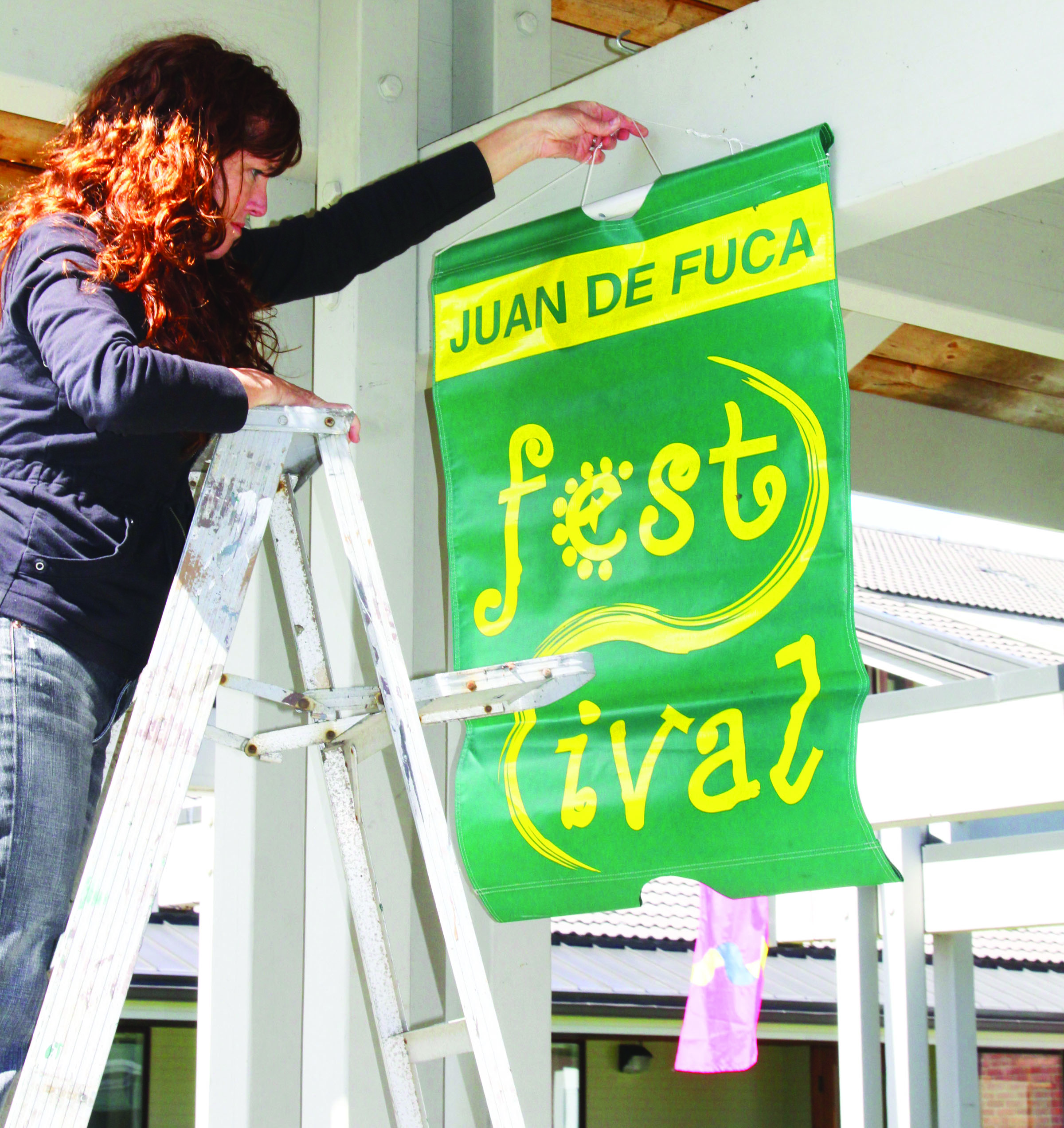 Sam Calhoun of Port Angeles hangs the first of many banners heralding the 20th annual Juan de Fuca Festival of the Arts. Calhoun organizes the scores of volunteers who put on the four-day festival