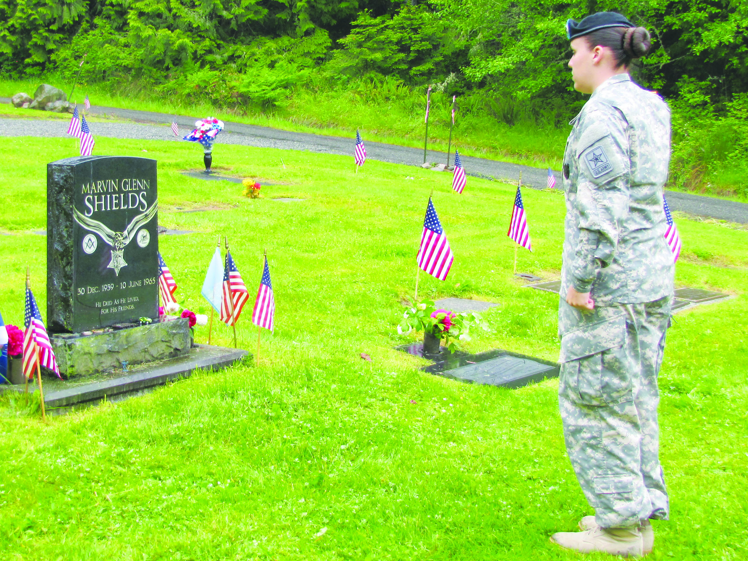 Army Staff Sgt. Tristan Ryan pays her respects at the gravesite of Marvin Glenn Shields after the Monday afternoon Memorial Day ceremony in Gardiner.  -- Photo by Arwyn Rice/Peninsula Daily News