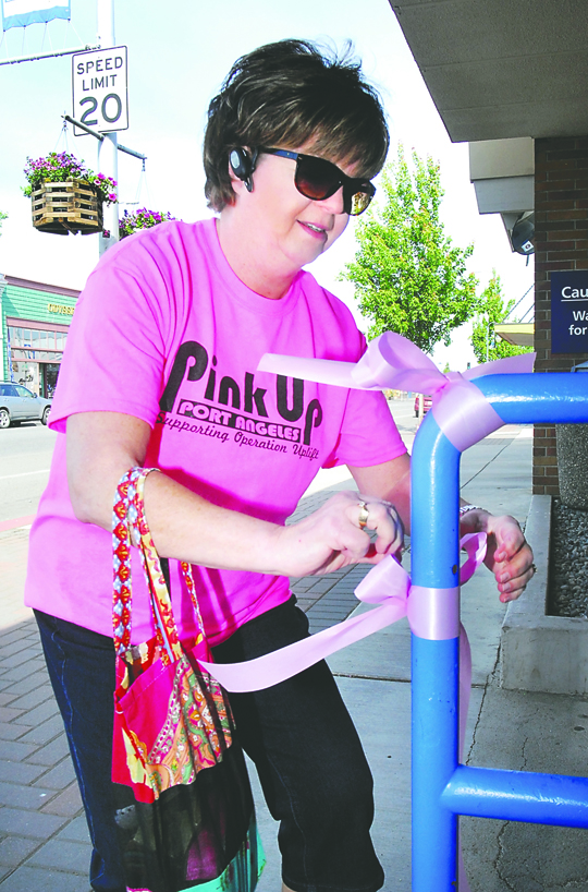 Wendy Shea ties pink ribbons around a railing in downtown Port Angeles in 2013 to kick off the annual Pink Up Port Angeles fundraising campaign for Operation Uplift. Keith Thorpe/Peninsula Daily News