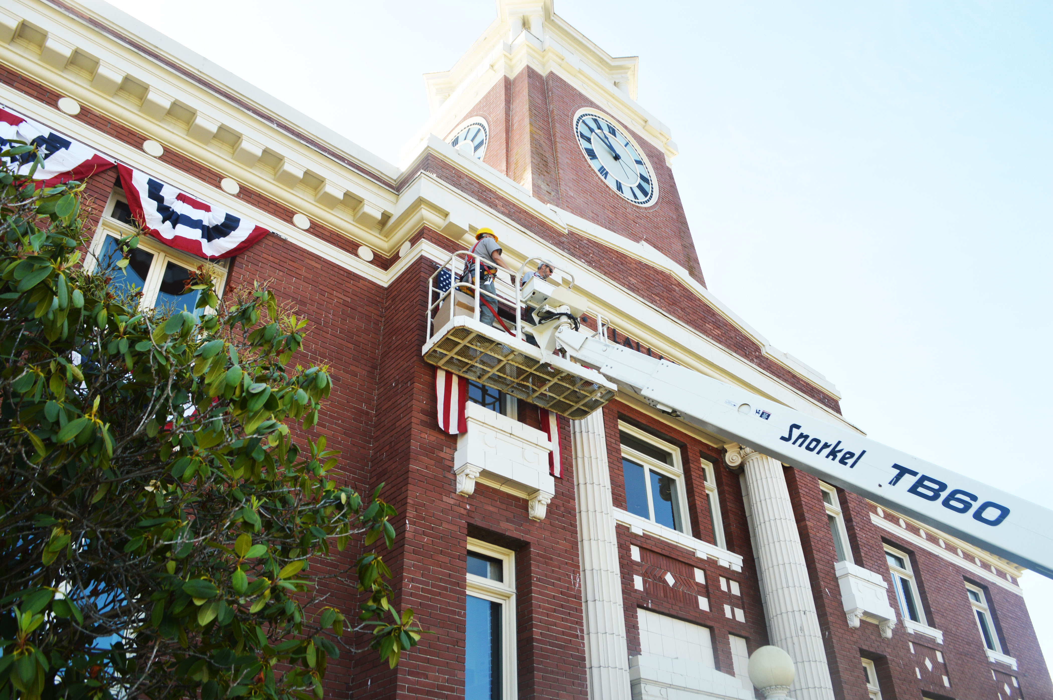 Clallam County maintenance workers Gary Menkal and Todd Bryant post bunting on the front of the county courthouse in Port Angeles on Monday morning in preparation for Independence Day on Friday. The Port Angeles Fourth of July parade will pass in front of the building at 6 p.m. before heading west on First Street through downtown. Joe Smillie/Peninsula Daily News