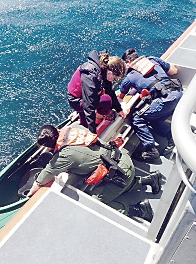 Crew members of a 45-foot response boat-medium based at Air Station/Sector Field Office Port Angeles pull two kayakers onto their boat Tuesday morning. U.S. Coast Guard