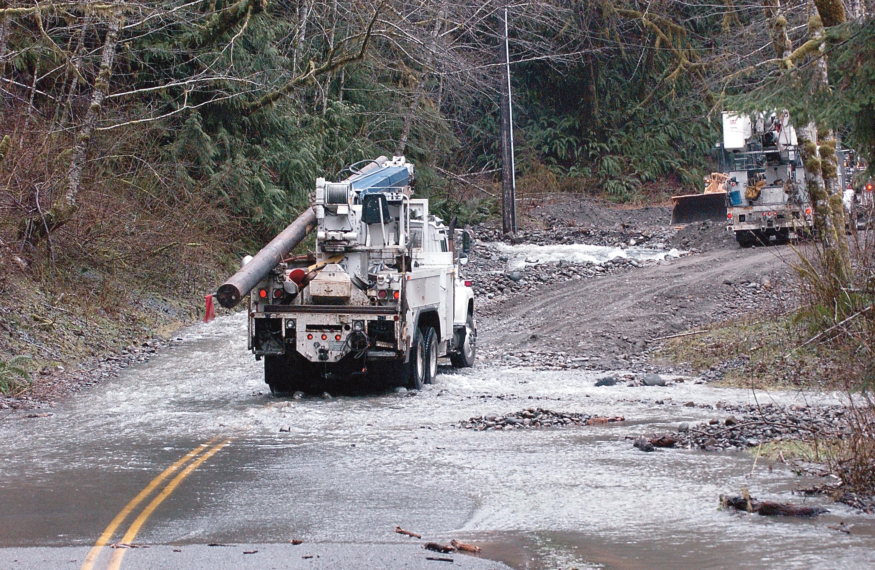 Clallam County PUD trucks drive past a washout on the Upper Hoh Road in January 2009 en route to another washout upstream where power had been knocked out. Lonnie Archibald/Peninsula Daily News