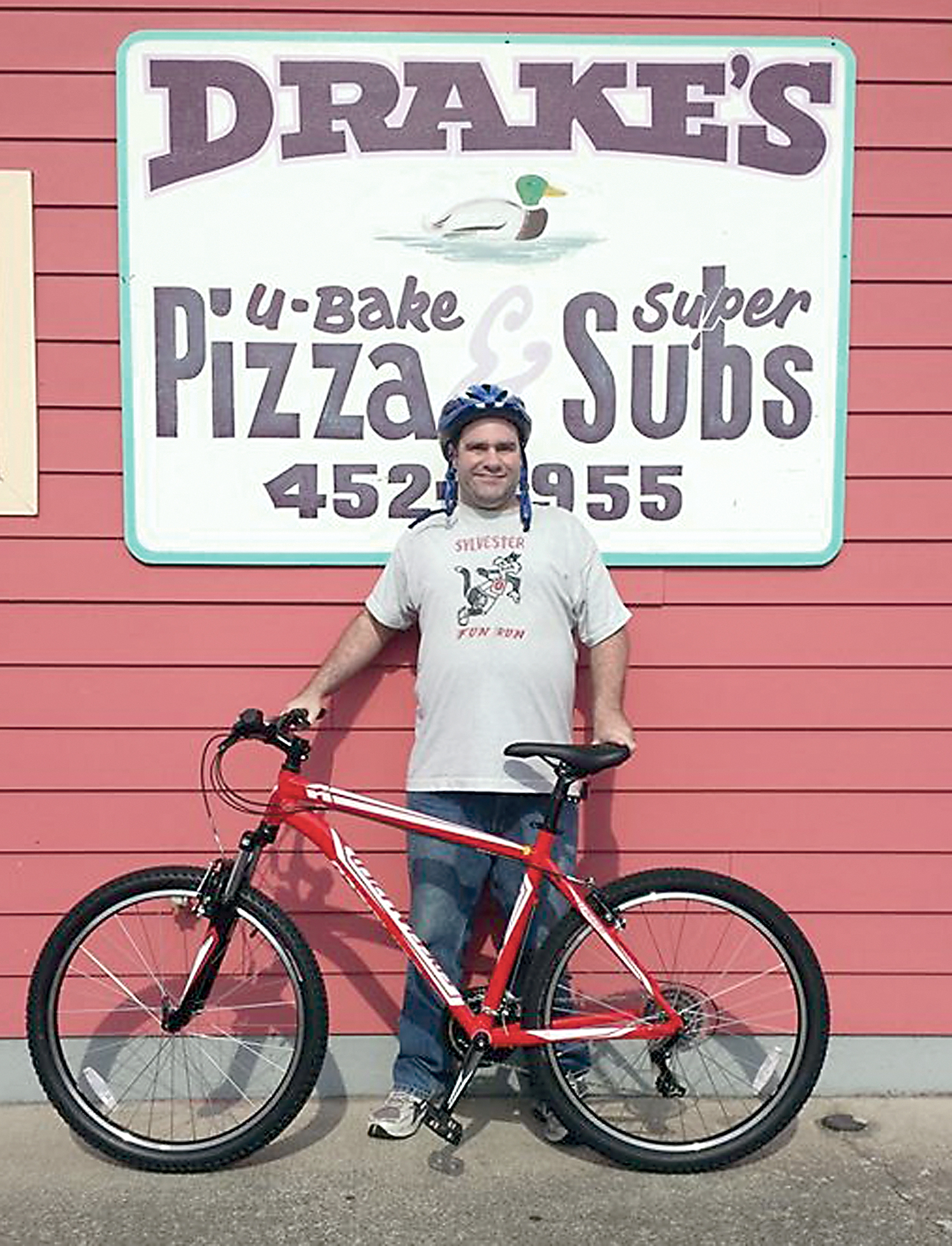 Chris Guillory stands outside Drake’s U Bake Pizza and Subs with the new bicycle for which the staff and customers of the eatery raised funds to purchase after Guillory’s own bicycle was stolen. — Drake’s U Bake Pizza and Subs