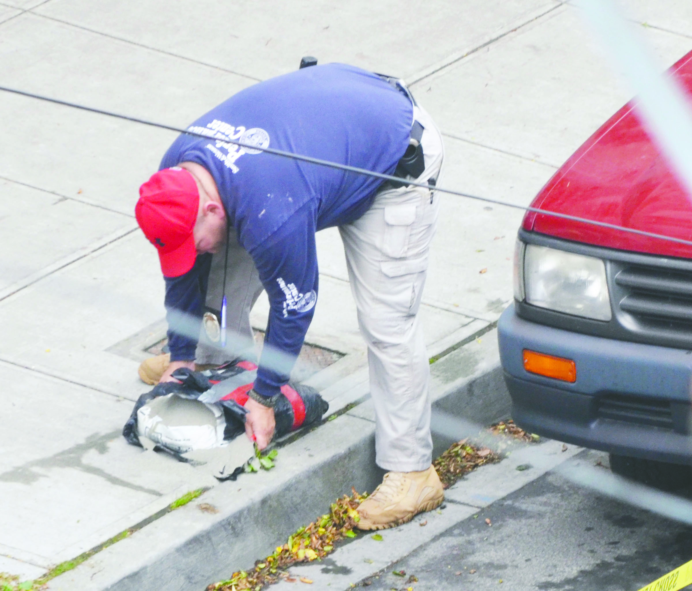 Port Townsend Police Officer Matt Krysinski prepares to lift a suspicious package that turned out to be a bag of sand.  -- Photo by Charlie Bermant/Peninsula Daily News