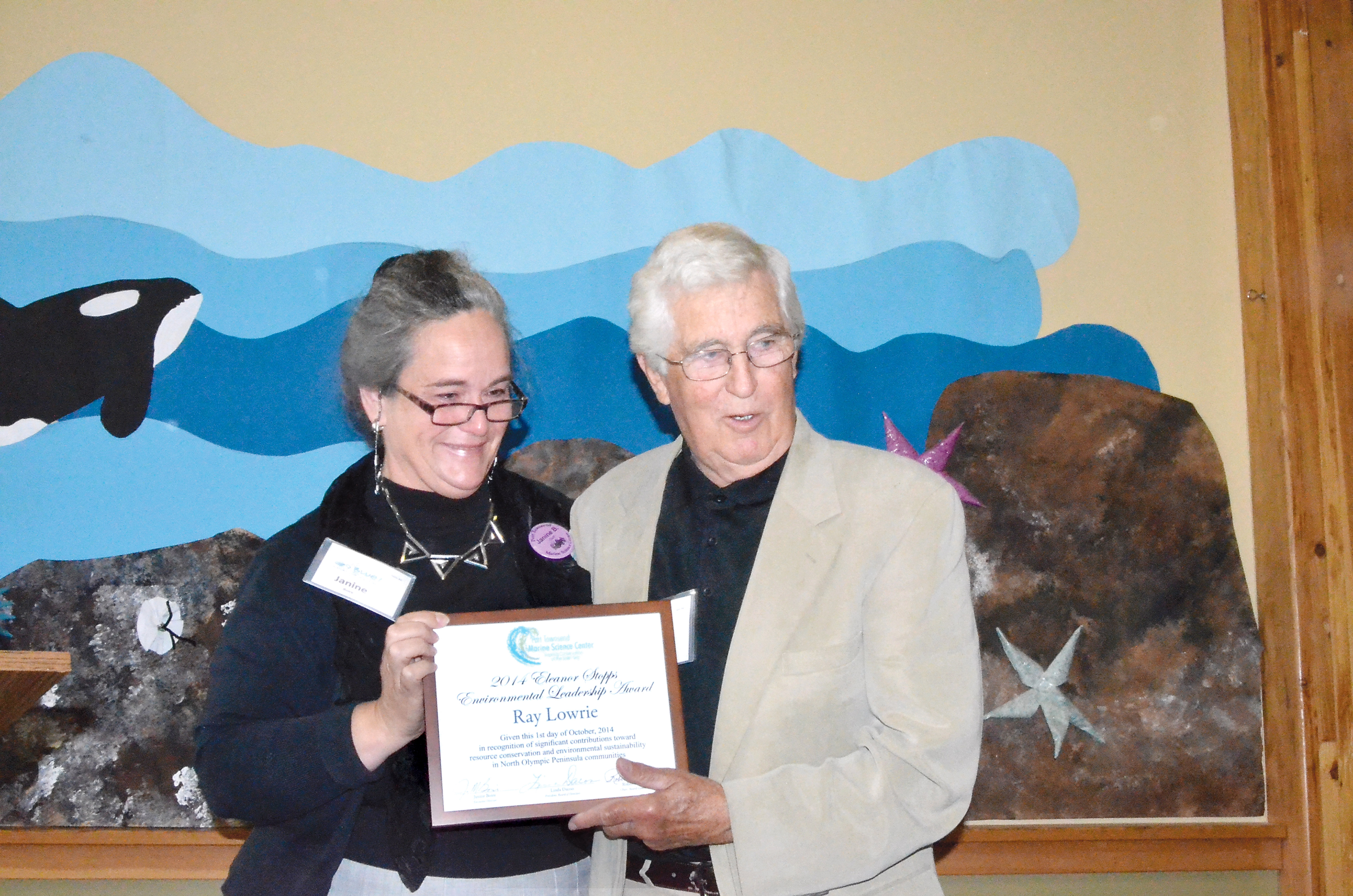 Port Townsend Marine Science Center Executive Director Janine Boire presents the 2014 Eleanor Stopps Environmental Leadership Award to Ray Lowrie on Wednesday. Charlie Bermant/Peninsula Daily News