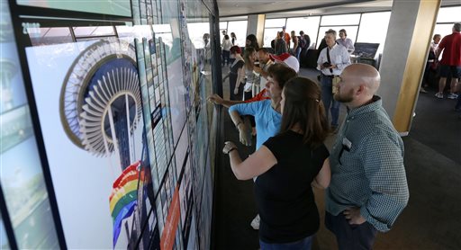 Visitors to the Space Needle in Seattle interact with a large touch-screen photo display wall that lets visitors see historical photos as well as photos shared by other visitors. — Photo by Ted S. Warren/The Associated Press
